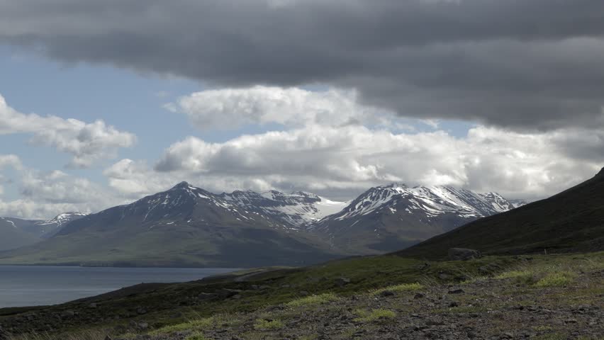 Wide Shot of Majestic Icelandic Mountains and Lake Under a Dramatic Cloudy Sky