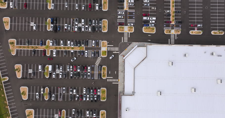 Large outdoor parking lot full of cars at shopping mall retail center, showing commercial success, consumer behavior and suburban development.