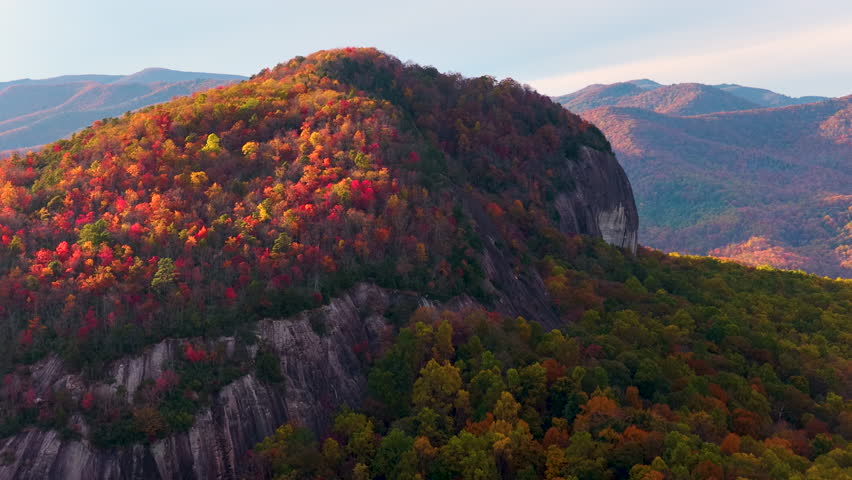 Sunset autumn view of Looking Glass Rock surrounded with Appalachian forest hills. Lush woods with golden trees in colorful fall season.