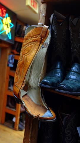 Worn cowboy boot displayed inside Chicago western store. Close view shows a tan leather shaft with missing upper material beside polished black footwear.