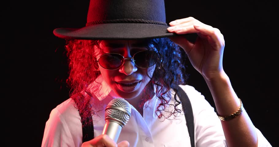 Professional singer performing on dark background with color lights, closeup