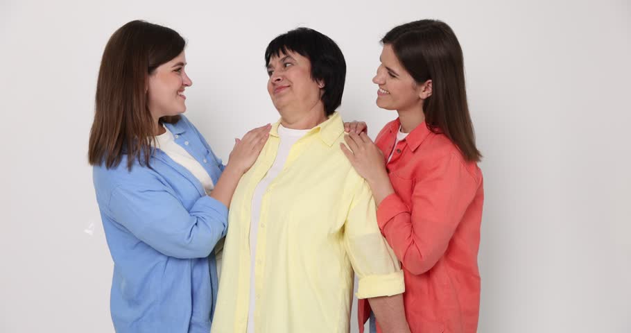Happy family. Twin sisters and their mother on light background