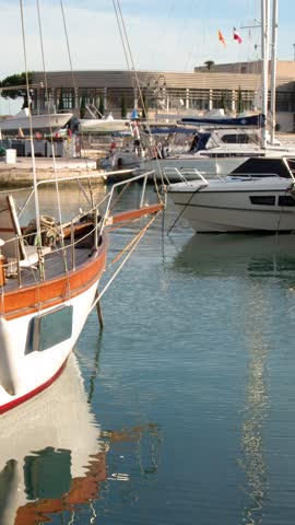 A vintage wooden yacht floats in calm harbor waters under bright daylight with slow panning.