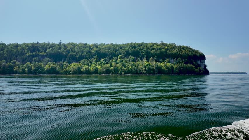 View from the waters of Green Bay looking toward the forested shoreline and limestone bluffs of Peninsula State Park in Door County, Wisconsin.