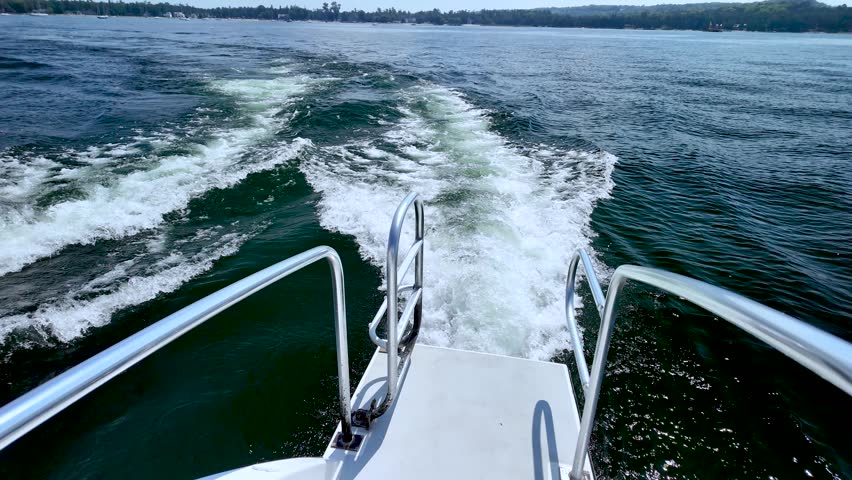The wake churns behind a boat on Green Bay before the view pans toward Peninsula State Park and Horseshoe Island on a beautiful Door County summer day.