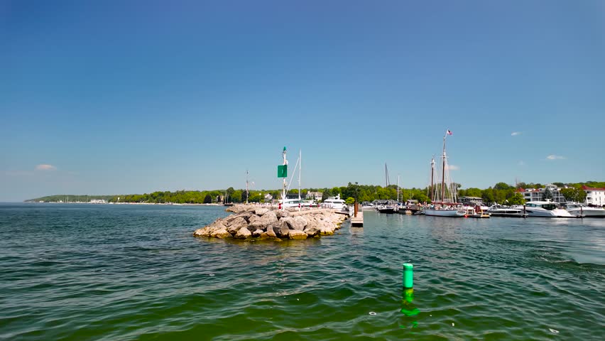 A scenic boat leaves Sister Bay Marina, passing docked vessels and the harbor rock breakwater before cruising into the open waters of Green Bay, Wisconsin.