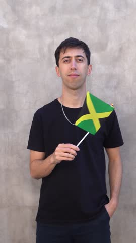 Adult person waving the Jamaican flag. Vertical shot in slow motion.