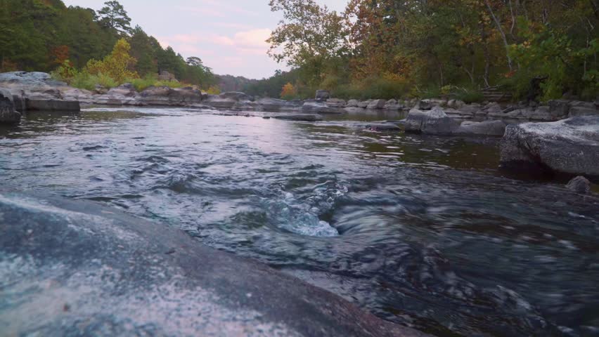 Peaceful Wilderness River Flowing Over Rocks at Dusk
Description: This serene nature clip highlights the tranquil, steady flow of a wilderness river carving through a craggy bed of dark boulders.