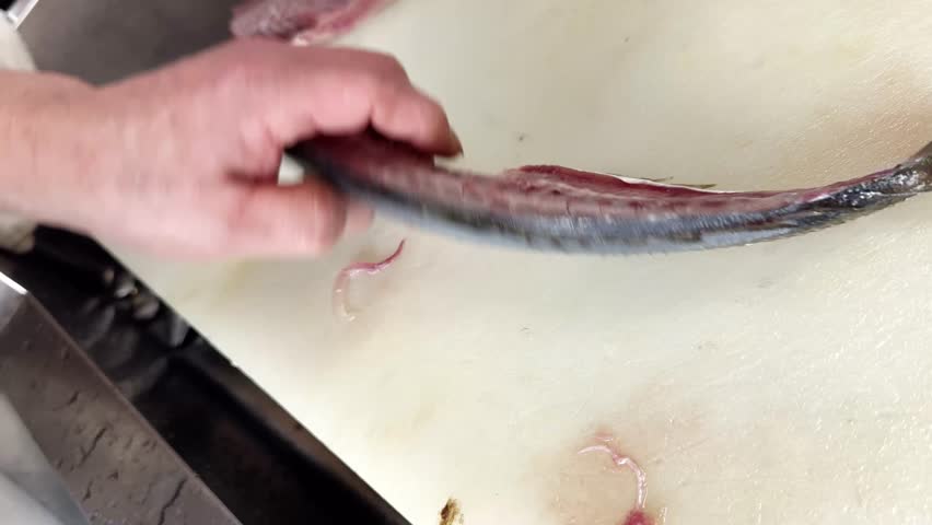 Japanese Chef Prepares Whole Horse Mackerel Part 10 of 12: Filleting The Other Side, Japan. A Japanese izakaya chef fillets the other side of the fish off the backbone with a knife, one clip of a 12-clip series showing the complete process of preparing a whole fresh horse mackerel from scaling to filleting.