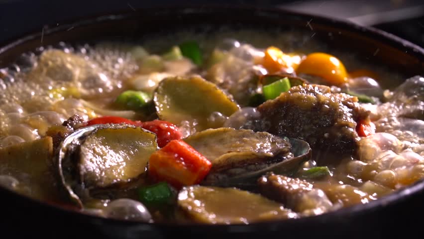 Boiling korean abalone seafood stew in a traditional earthenware pot