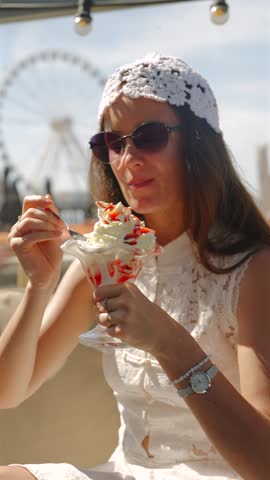 Woman In White Dress Enjoying A Sweet Treat Near A Ferris Wheel