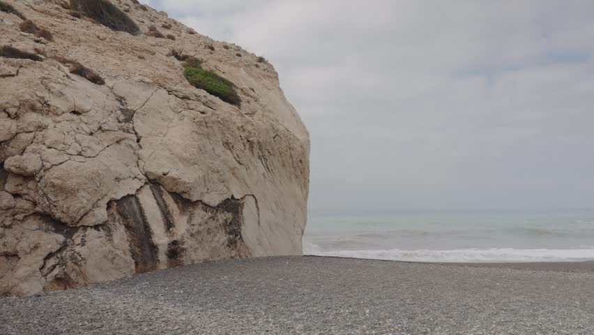 Peaceful seaside scene with waves gently washing over the shore and large rocks near the coastline