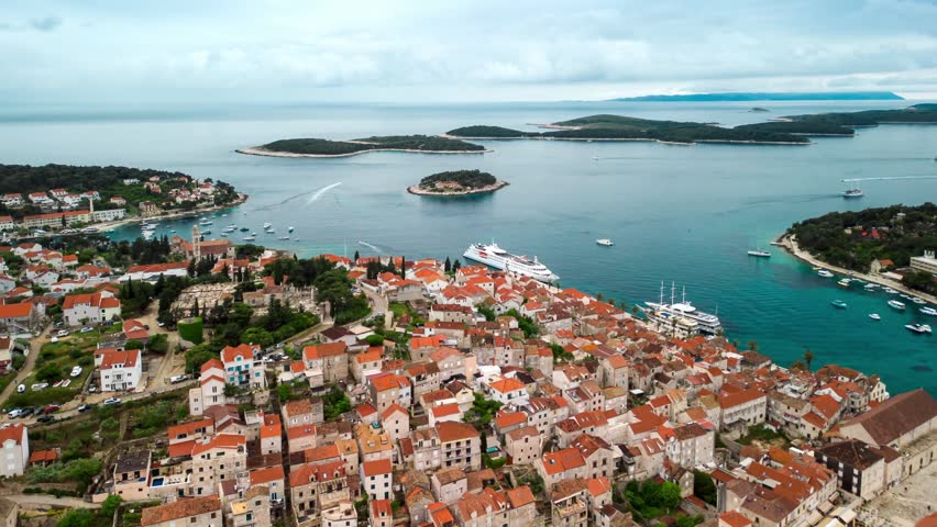 View of the historic town of Hvar with its terracotta rooftops, stone buildings, and harbor filled with boats, overlooking the Adriatic Sea in Hvar, Croatia.