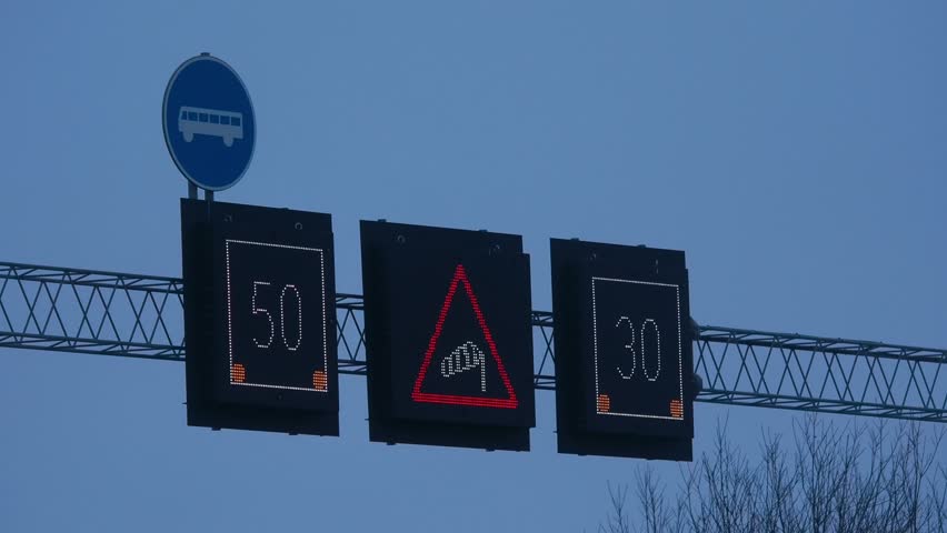 View of digital traffic signs displaying speed limits and a warning symbol on a gantry in Gothenburg, Vastra Gotaland County, Sweden.