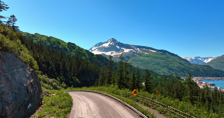 Wavy road in the spectacular mountains among the pine tree woods. Amazing nature landscape of Alaska.