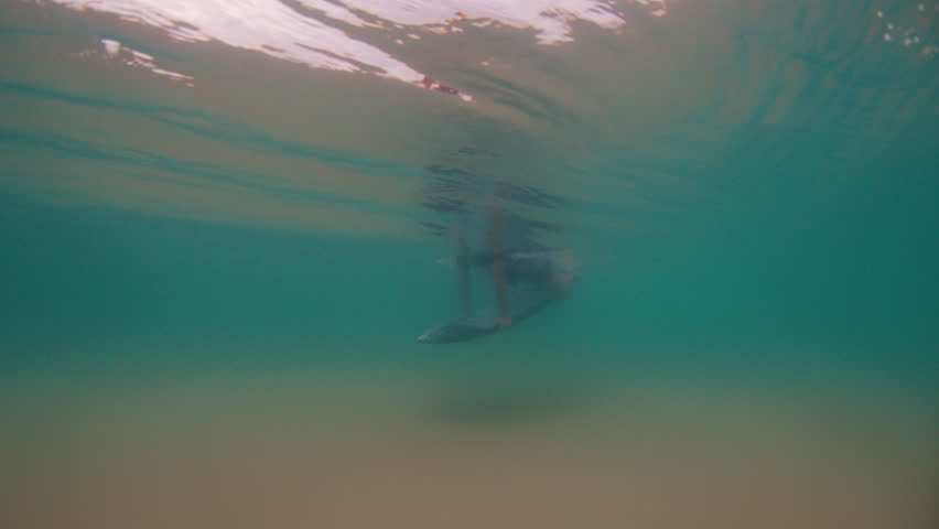 Surfer dives under the wave. Underwater footage of the surfer diving under the wave with surfing board
