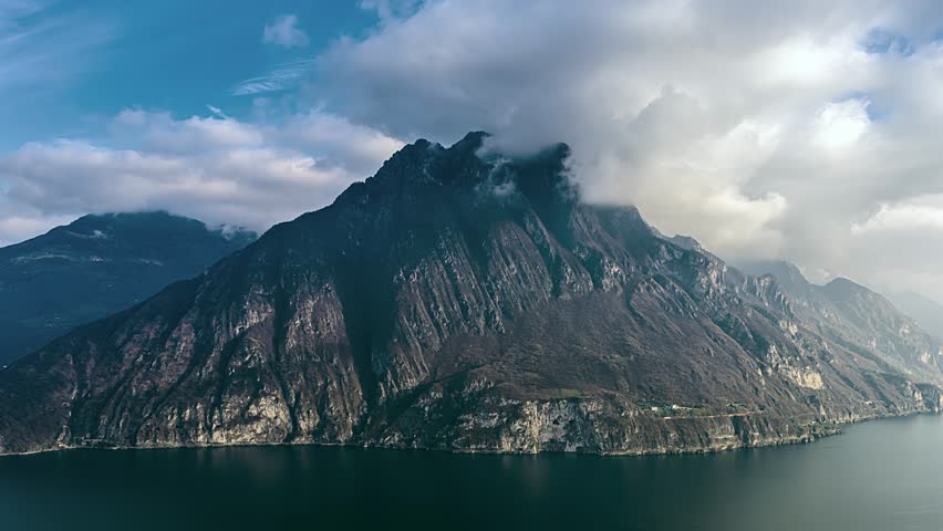 Aerial view of Lake Como with dramatic mountain peaks and clouds reflecting over the water in Lombardy, Italy.