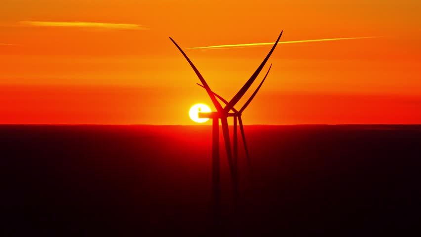 Aerial view of wind turbine silhouette against a vibrant sunset over the peat bog landscape of Kaigu Purvs in Livberze parish, Jelgava Municipality, Latvia.