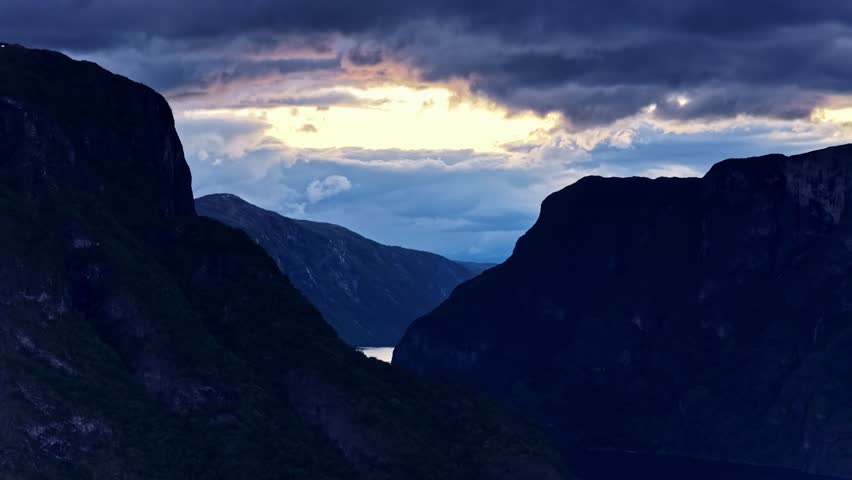 Aerial view of dramatic mountains and dark clouds over the Aurlandsfjord at sunset in Flam, Vestland, Norway.
