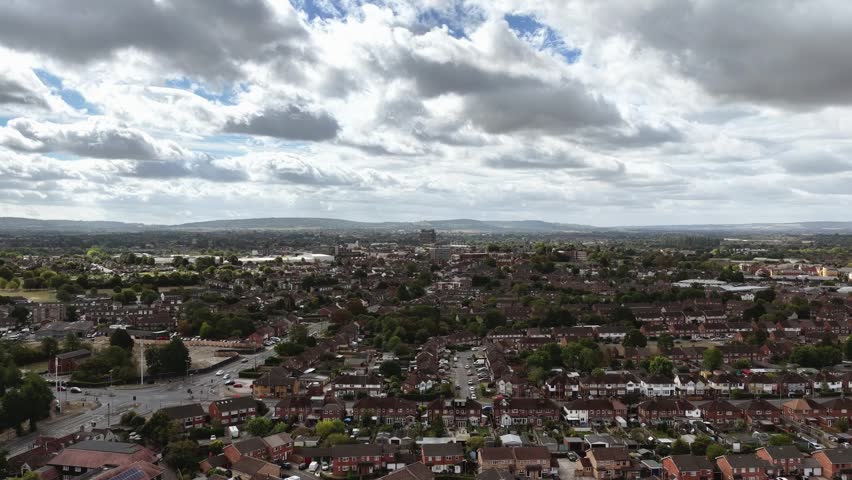 A dense urban town with rows of houses stretches to the horizon under dramatic cloudy skies
