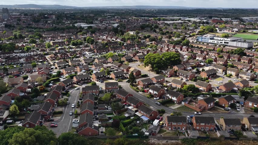 A dense urban town with rows of houses stretches to the horizon under dramatic cloudy skies