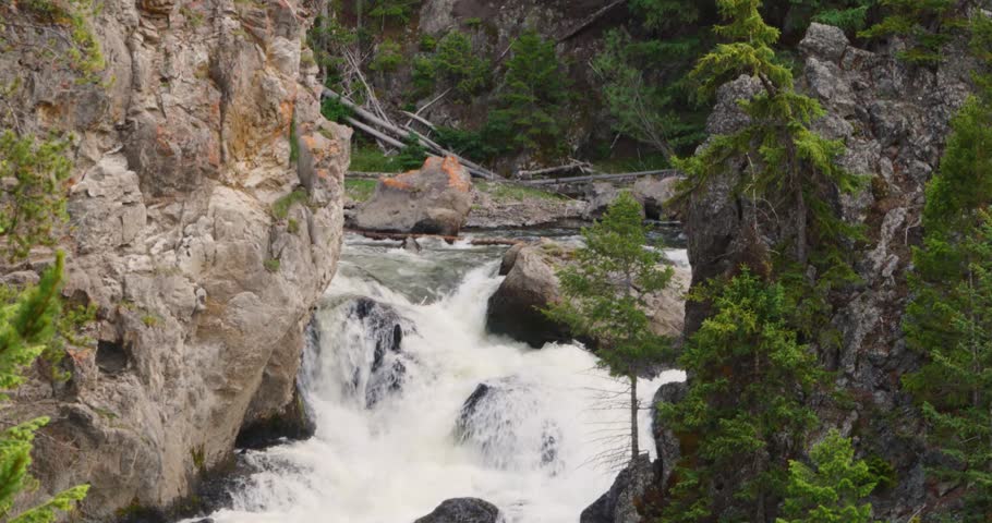 A crisp shot centered on the chaotic white water rapids winding past dark boulders down a rocky canyon floor.