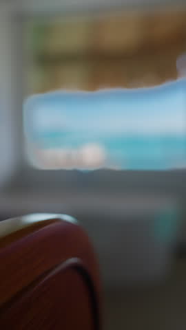 Vertical Screen: Bora Bora luxury resort bathroom featuring modern freestanding white bathtub with towel and chrome fixtures overlooking turquoise lagoon through large window with thatched palm roof.