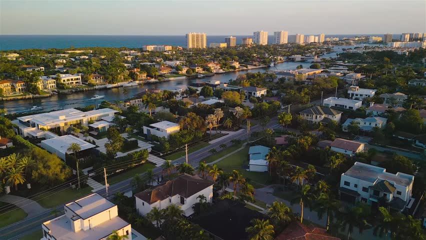 Aerial view of a residential neighborhood with houses, palm trees, and a canal in Boca Raton, Florida, United States.