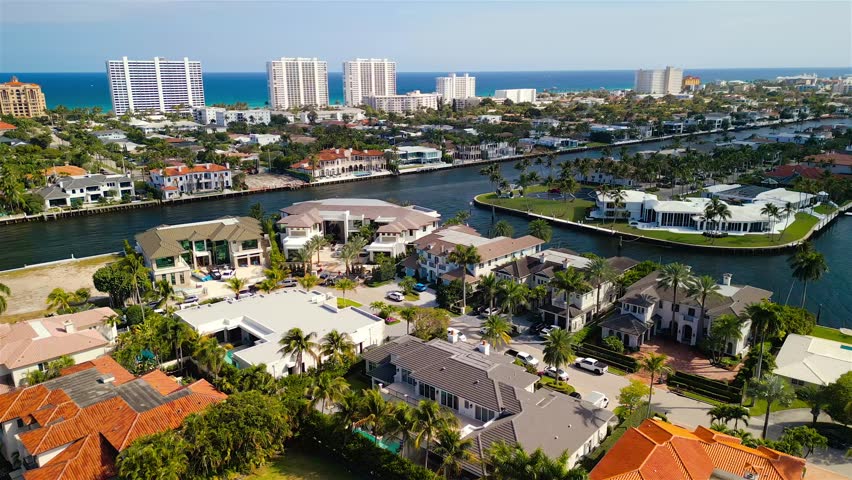 Aerial view of luxury waterfront homes along the canal with palm trees and swimming pools in Boca Raton, Florida, United States.