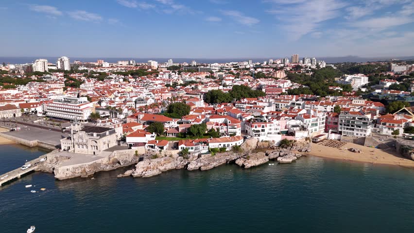 Aerial view of the coastal town of Cascais with its historic architecture, red rooftops, sandy beaches, and rocky shoreline along the Atlantic Ocean in Cascais, Lisbon, Portugal.