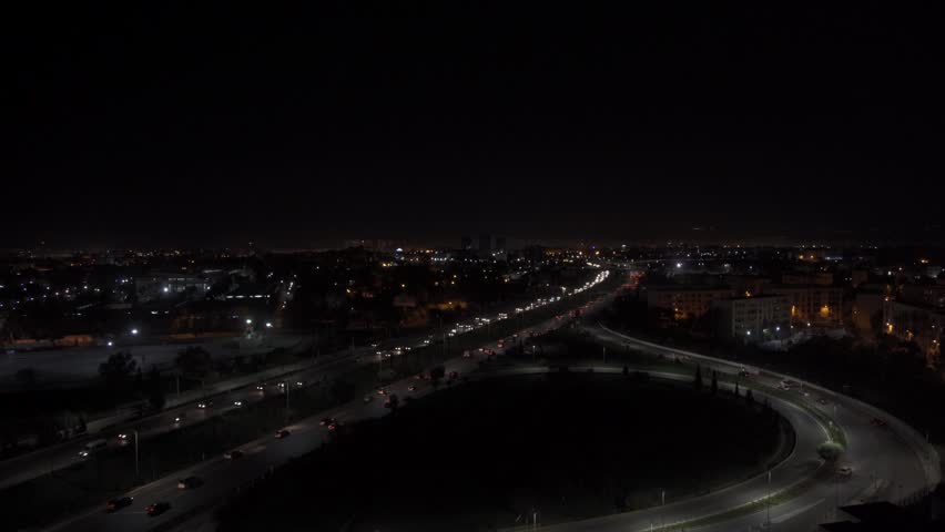 Aerial view of a highway interchange with illuminated roads and flowing traffic under the night sky in Algeria.