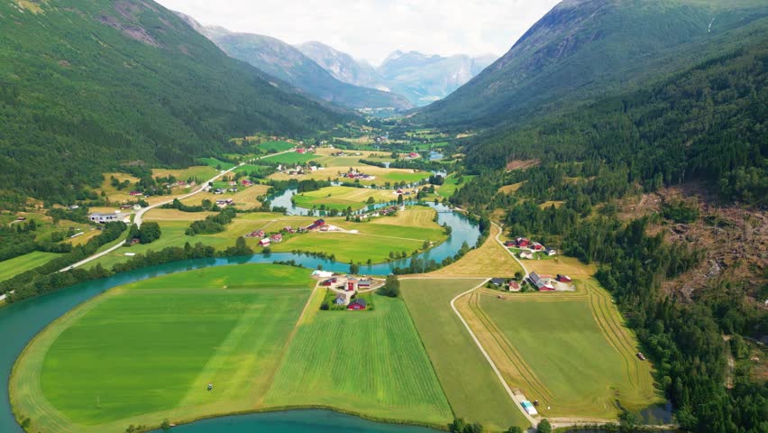 Aerial view of the lush Stryn valley with a winding river, green agricultural fields, and surrounding mountains in Stryn, Vestland, Norway.