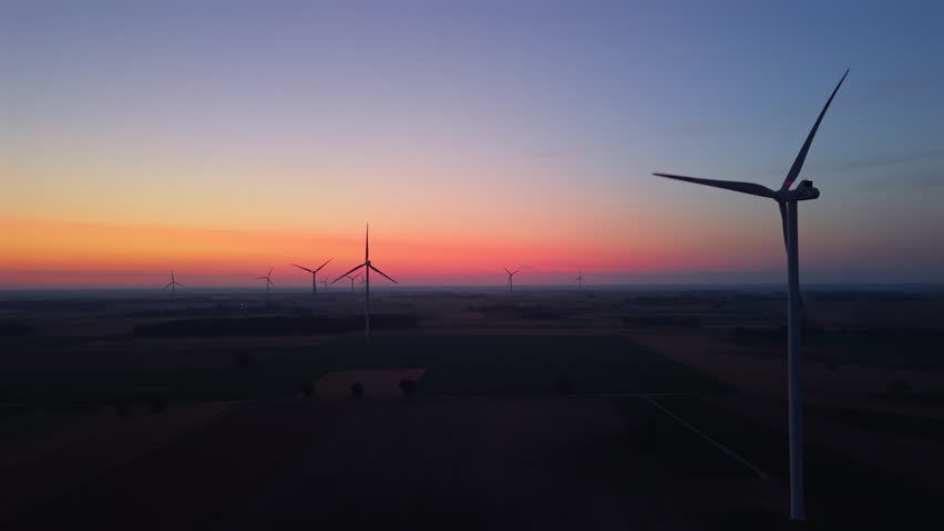 Wind farm, wind turbines, dawn, sunrise, rotating turbine blades, flashing red aviation lights, renewable energy, sustainable energy, clean electricity, green power, wind power generation, eco-friendly infrastructure, modern energy landscape, low-carbon future.