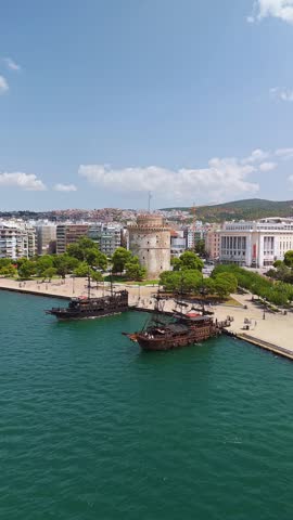 Aerial view of the White Tower landmark on the waterfront with pirate tour boats in Thessaloniki, Greece