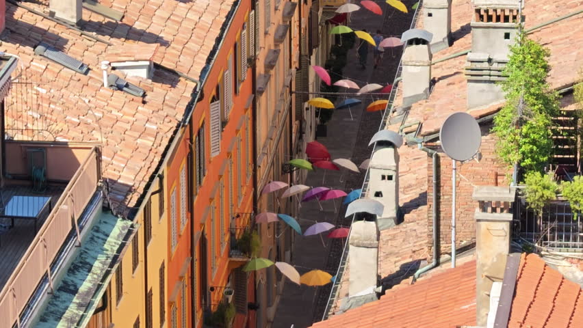 Panoramic view of view on umbrellas suspended above a street in Modena, Italy, with the Ghirlandina bell tower visible in the background of Modena city in Italy