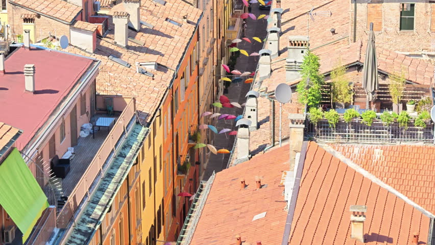 Panoramic view of view on umbrellas suspended above a street in Modena, Italy, with the Ghirlandina bell tower visible in the background of Modena city in Italy