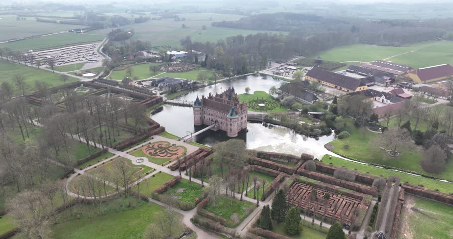 An Aerial view of Slot Egeskov Castle in Denmark surrounded by gardens, moat, and scenic farmlands