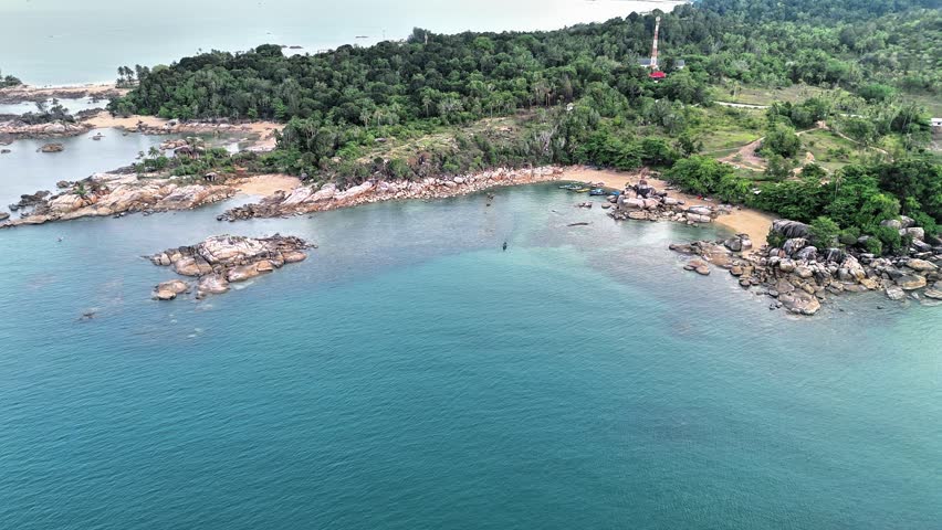 Enjoy an immersive aerial journey above the stunning coastline of Turun Aban Beach in Sungailiat, Bangka, Indonesia. This cinematic drone footage captures a pristine tropical bay where crystal-clear turquoise water gently surrounds impressive granite rock formations, secluded sandy beaches, and lush coastal forest. The elevated perspective highlights the unique combination of rugged shoreline, shallow reefs, hidden coves, and tranquil ocean scenery that makes this destination one of the island