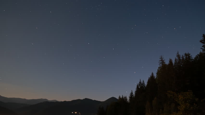 Star filled night sky stretches above dark mountain and forest silhouettes, Wide landscape view captures a dense star field over a remote highland horizon