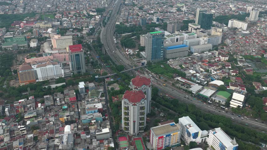 High aerial perspective flying over the sprawling urban landscape of jakarta, indonesia, showing a mix of modern skyscrapers and dense housing