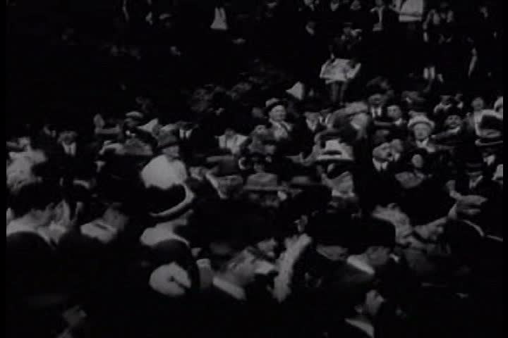 1910s - A steam train comes into town and a crowd waves at the passengers
