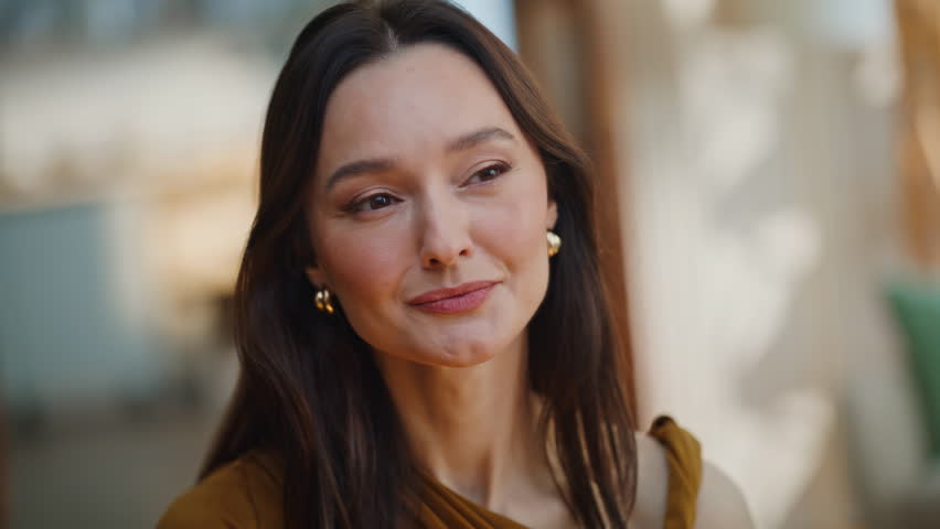 Elegant brunette looking mirror touching gold earrings closeup. Gorgeous lady smiling softly checking appearance makeup home. Attractive classy woman enjoying luxury accessories and feminine beauty.