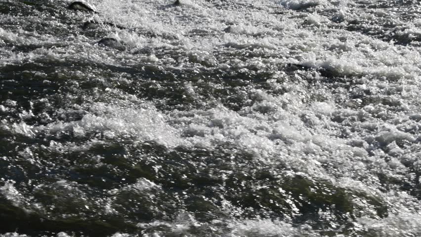 Senior man fly fishing in a fast flowing mountain river at sunset.