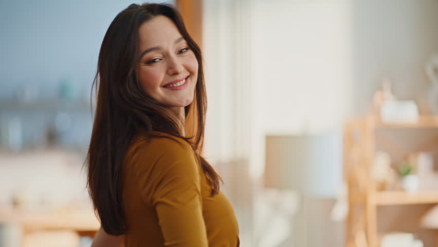 Happy woman twirling mirror trying elegant dress in modern apartment bedroom closeup. Gorgeous brunette admiring trendy gown home getting ready to party. Feminine fashion beauty and stylish wardrobe.