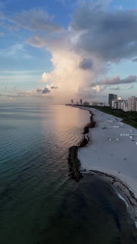 A Vertical aerial view of Miami Beach with turquoise waters meeting wide white sandy coastline