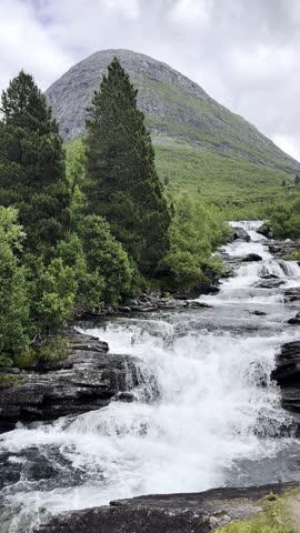 Crystal-clear water cascades down steep mountain slopes, forming beautiful waterfalls among rugged rocks and pristine Norwegian nature. Spectacular Scandinavian landscape with flowing water, dramatic scenery, and untouched wilderness.