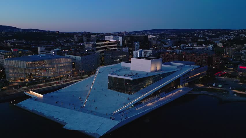 Aerial view of the illuminated Oslo Opera House with its iconic sloped roof and modern architecture along the waterfront in Oslo, Oslo, Norway.