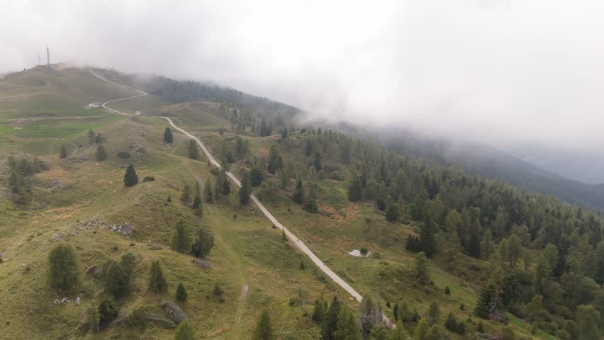 4K cinematic drone shot of a winding mountain road with fog, hills and forest. Ideal for stock footage and travel projects.