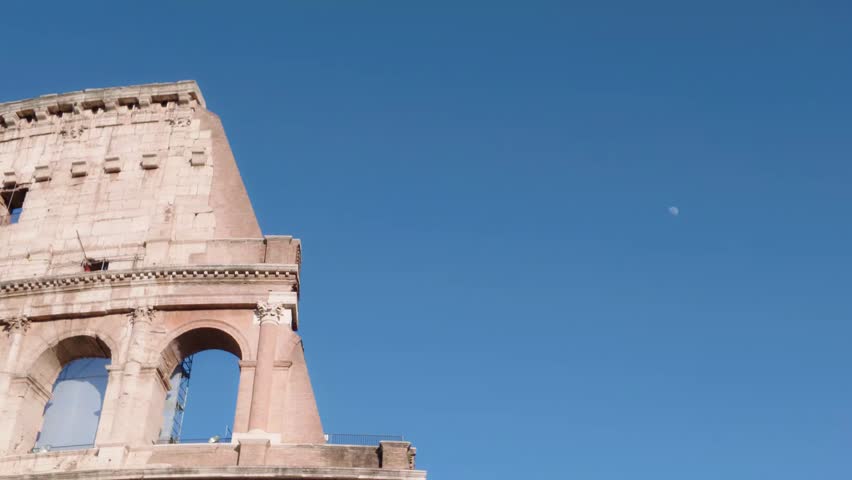 Close-up view of the iconic Colosseum in Rome, Italy, showcasing its ancient Roman arches and weathered stone facade beneath a clear blue sky on a sunny day.