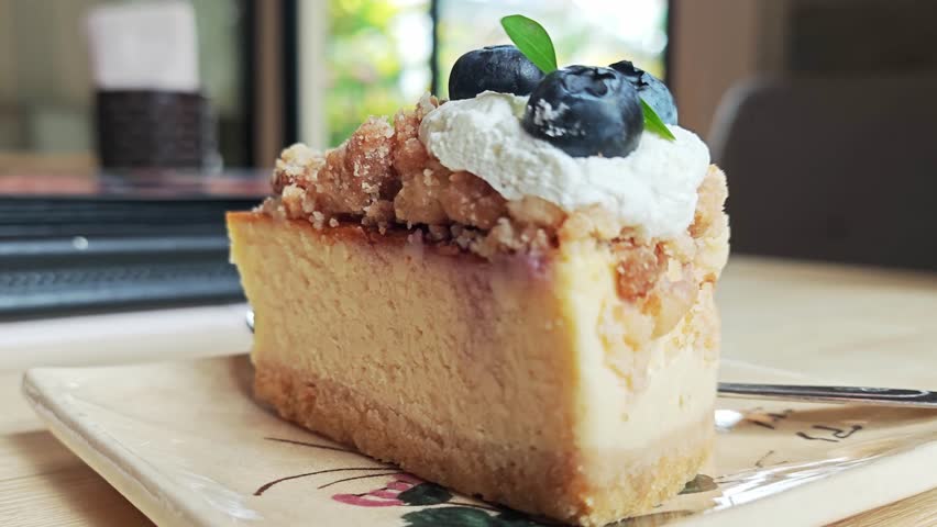Delicious Blueberry Crumble Cheesecake Slice with Whipped Cream.